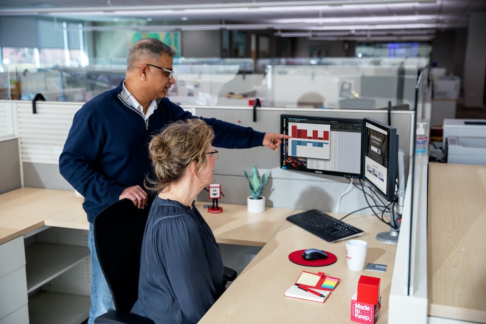 A man and woman working at a desk in an office.