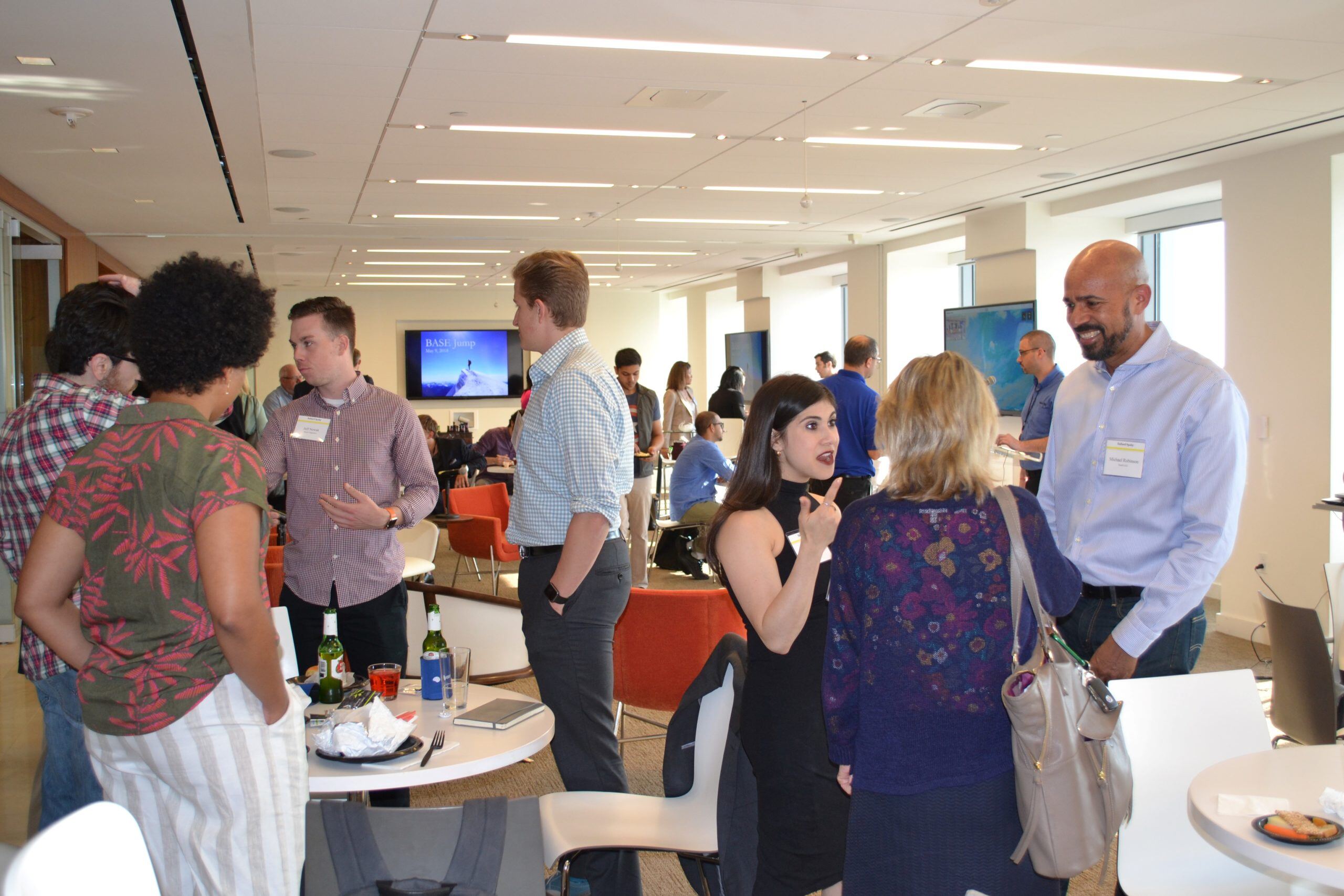 A big group of people standing by tables and talking to each other at an event.